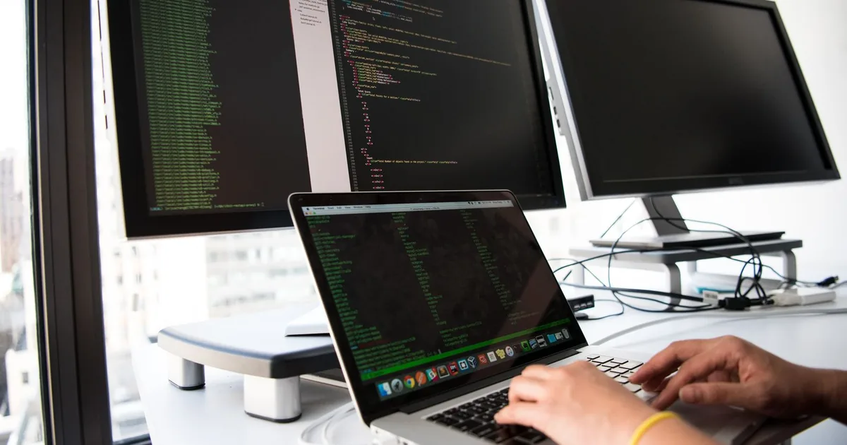 Content editor working on a laptop with a clean white desk setup.