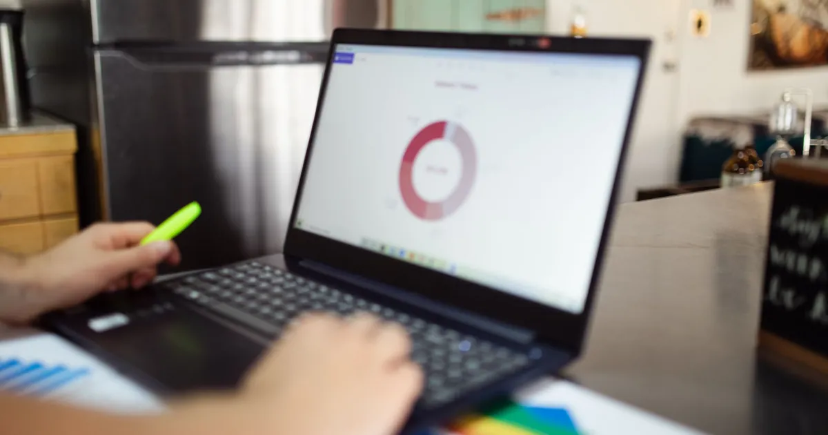 Person analyzing business data on a laptop in a modern indoor setting.